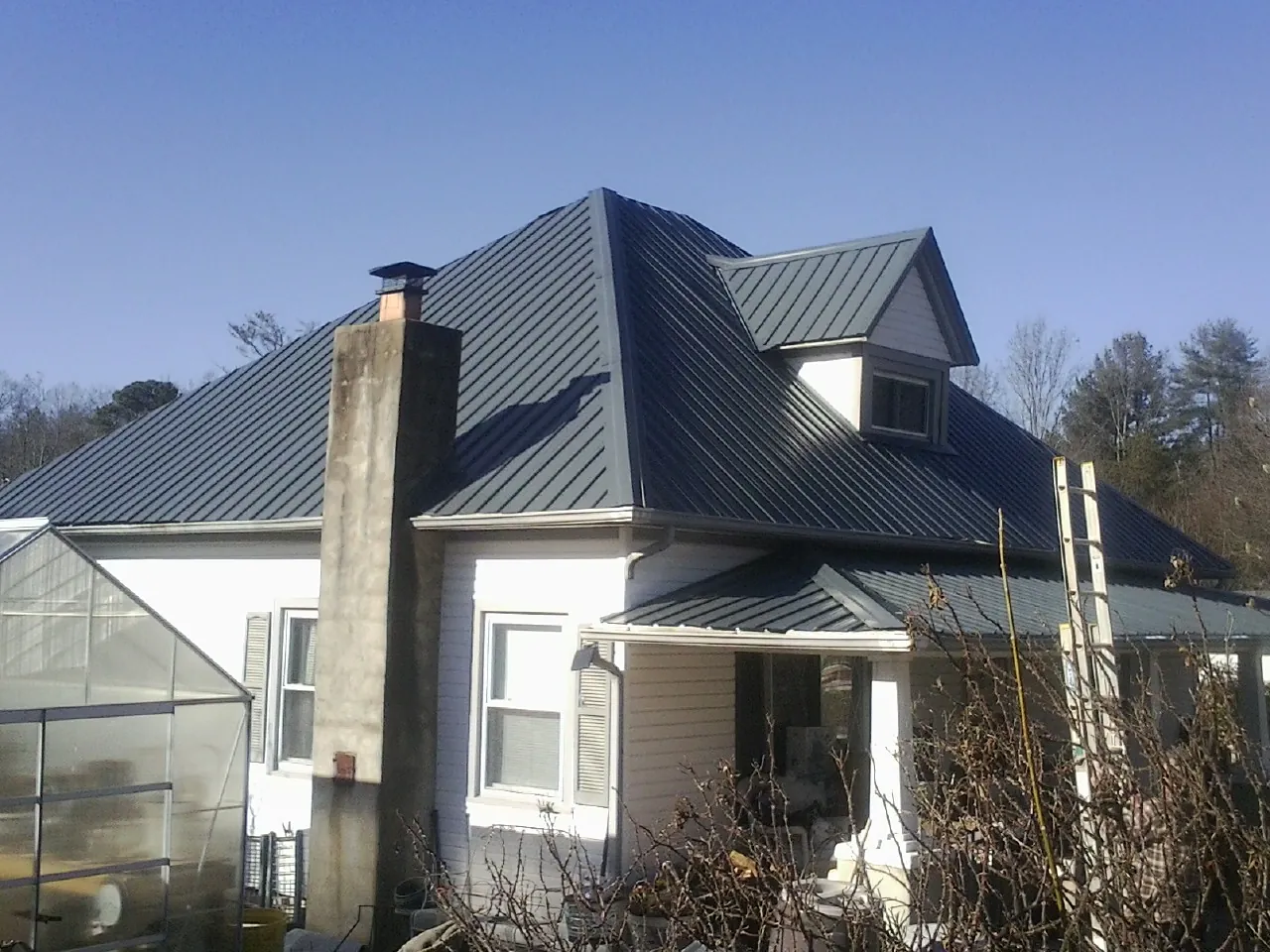 Dark blue standing seam metal roof on a white farmhouse with dormer — Slate & Tile Roof Repair by Roofing Brothers in Guerneville