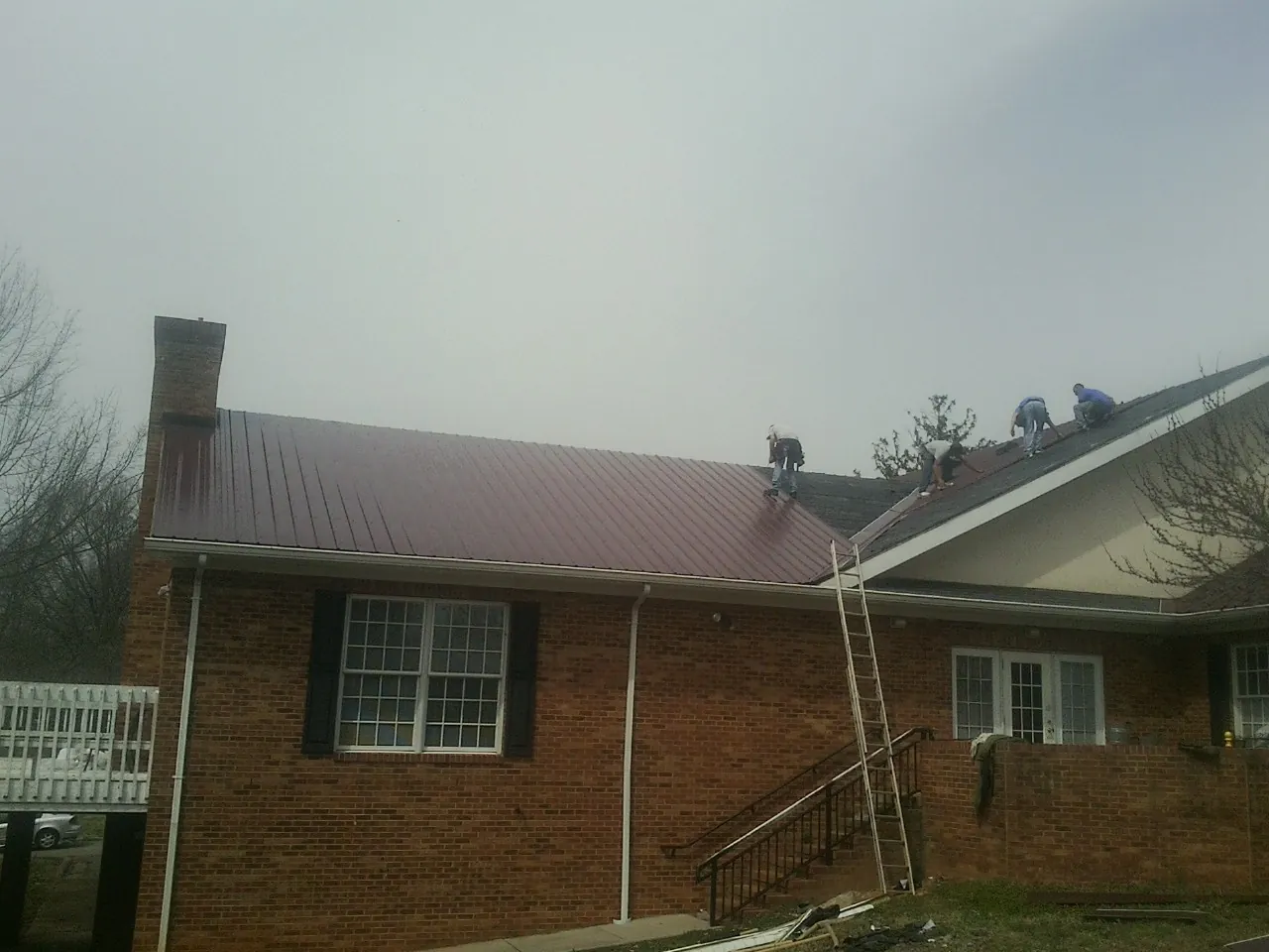 Crew setting red metal roofing panels on a brick home in Guerneville