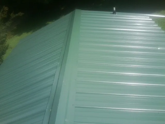 New green metal panels meeting at the ridge of a roof — Flat Roof Repair work by our crew in Guerneville