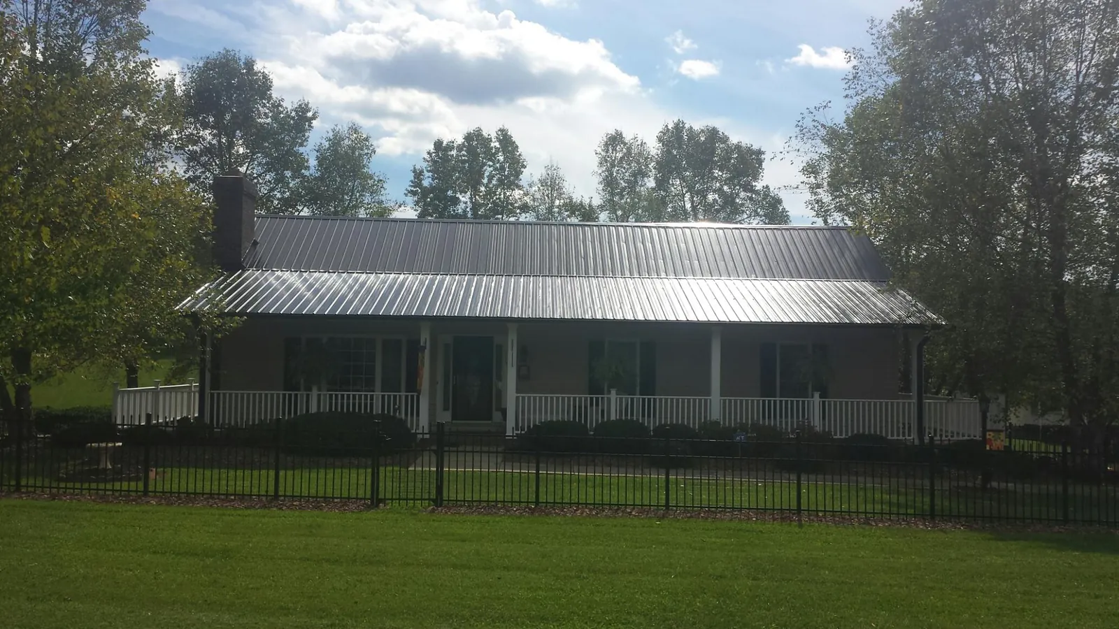 Gray metal roof on a brick ranch with a full width front porch — Gutter Guard Installation work by our crew in Guerneville