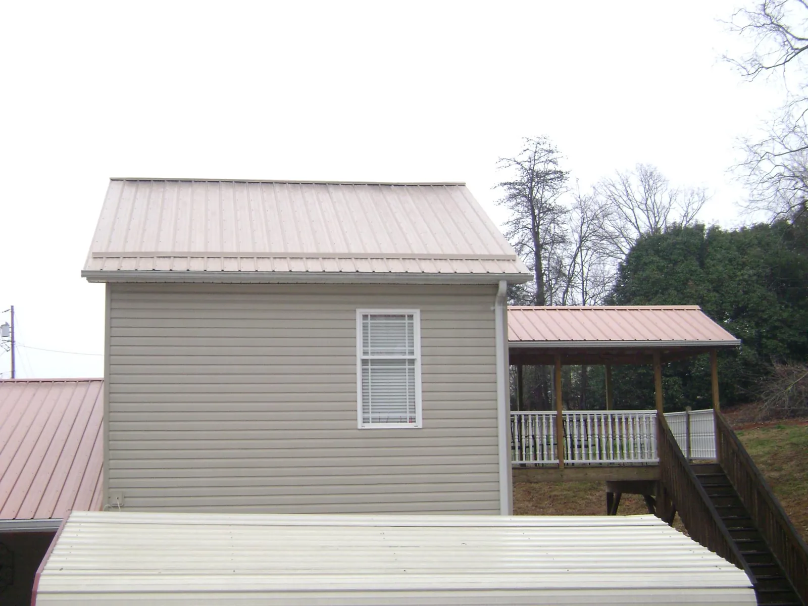 Tan metal roofs on a two story addition and attached porch, from a Roof Replacement job in Guerneville