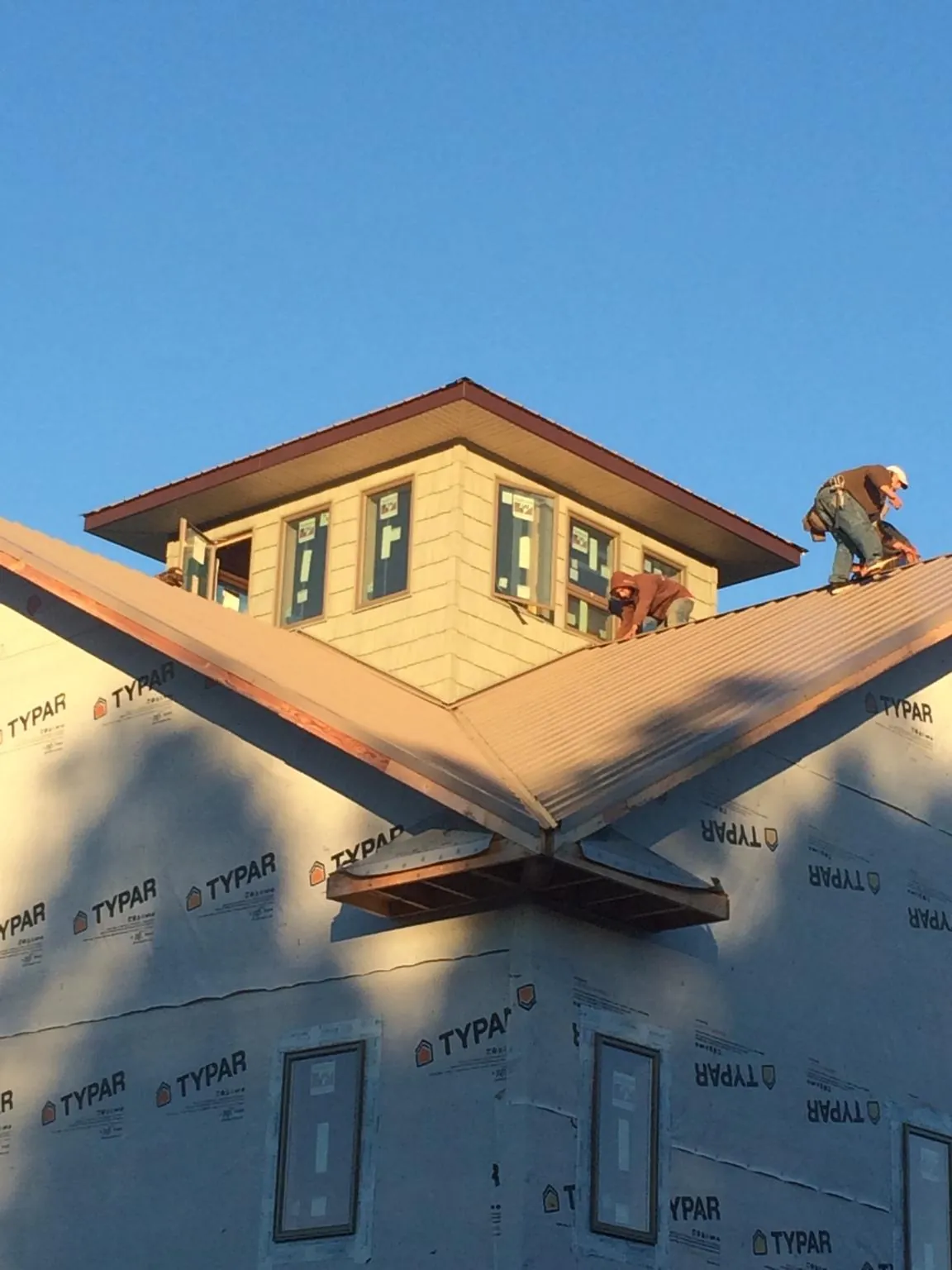 Roofers working around a rooftop cupola on a new metal roof at sunset — Roof Waterproofing in Guerneville by Roofing Brothers